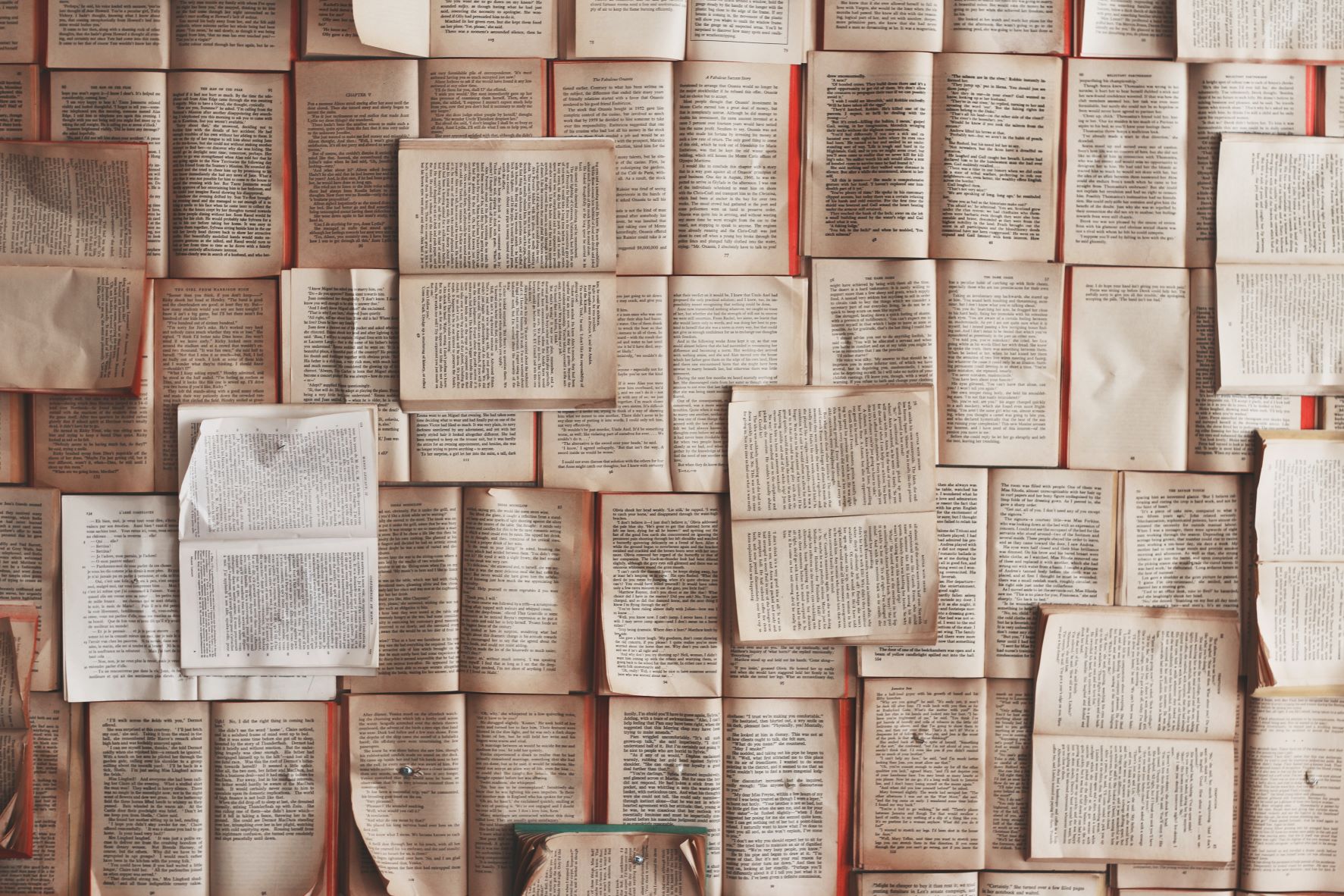 Foto mit vielen älteren Büchern, die teils vergilbte Seiten haben und aufgeklappt nebeneinander und aufeinander liegen